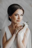 uma mulher vestindo uma branco vestir e uma véu é segurando uma flor dentro dela mão foto