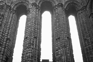 antigo pedra arcos com alta janelas dentro Preto e branco dentro Tynemouth convento e castelo foto