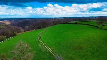 cênico campo panorama com exuberante verde Campos, uma enrolamento caminho, e uma vibrante azul céu com espalhados nuvens. ideal para fundos e natureza temas. foto