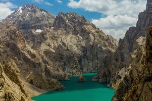 controlo remoto canto, Kel-su lago, escarpado penhascos, reflete uma grande, Claro céu. turquesa bacia mentiras escondido dentro áspero terras altas dobras, pacífico retiro. turistas e alpinistas em a costa admirar a beleza foto