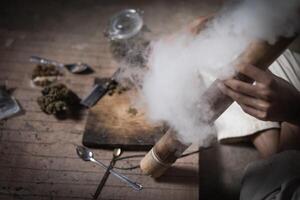 uma homem prepara maconha em uma corte borda para fumaça, pessoa quem fuma drogas, droga viciado, drogas vício e retirada sintomas conceito. drogasinternacional dia contra droga Abuso. foto