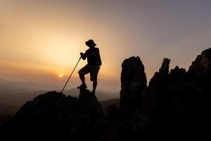 silhueta do caminhante em pé em topo montanha pôr do sol fundo. caminhante masculino caminhada vivo saudável ativo estilo de vida. foto