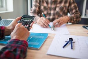 arquitetos e designers estão falando sobre construção planos antes ser entregue para a Engenharia equipe e capatazes para construção. auditar conceito planos a partir de uma equipe do arquitetos e designers foto