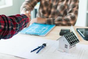 equipe do engenheiros e designers tem venha juntos para Projeto a energia salvando casa ou verde energia casa este usa natural energia tal Como vento turbinas e solar células para gerar eletricidade para lar. foto