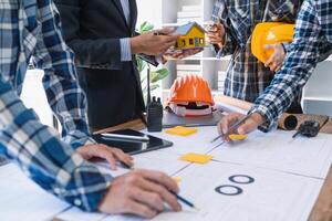 arquitetos e designers estão falando sobre construção planos antes ser entregue para a Engenharia equipe e capatazes para construção. auditar conceito planos a partir de uma equipe do arquitetos e designers foto