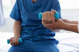 médico é ajudando uma paciente mover dela músculos depois de recuperando a partir de uma músculo prejuízo e querendo para reabilitar dela para estar capaz para usar dela normal diariamente vida com contínuo fisica terapia. foto