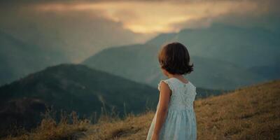 a menina carrinhos costas e parece às a montanha panorama. uma criança dentro uma branco vestir e curto corte de cabelo. foto