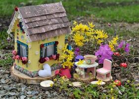 fofa fada boneca casa com Primavera flores lado de fora dentro a jardim. adorável miniatura para cumprimento cartões, Casamento ou aniversário conceito, real Estado, redução de tamanho, casa propriedade foto