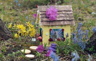 fofa fada boneca casa com Primavera flores lado de fora dentro a jardim. adorável miniatura para cumprimento cartões, Casamento ou aniversário conceito, real Estado, redução de tamanho, casa propriedade foto