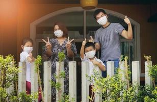 Família asiática usando máscara de proteção em pé de quarentena