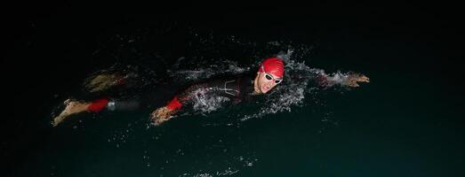 uma determinado profissional triatleta sofre rigoroso noite Tempo Treinamento dentro frio águas, exibindo dedicação e resiliência dentro preparação para a próximos triatlo nadar concorrência foto