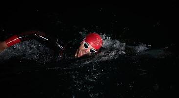 uma determinado profissional triatleta sofre rigoroso noite Tempo Treinamento dentro frio águas, exibindo dedicação e resiliência dentro preparação para a próximos triatlo nadar concorrência foto