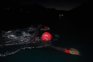 uma determinado profissional triatleta sofre rigoroso noite Tempo Treinamento dentro frio águas, exibindo dedicação e resiliência dentro preparação para a próximos triatlo nadar concorrência foto