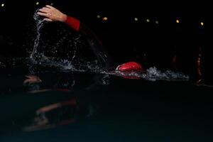 uma determinado profissional triatleta sofre rigoroso noite Tempo Treinamento dentro frio águas, exibindo dedicação e resiliência dentro preparação para a próximos triatlo nadar concorrência foto