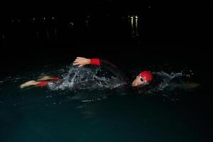 uma determinado profissional triatleta sofre rigoroso noite Tempo Treinamento dentro frio águas, exibindo dedicação e resiliência dentro preparação para a próximos triatlo nadar concorrência foto