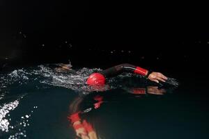 uma determinado profissional triatleta sofre rigoroso noite Tempo Treinamento dentro frio águas, exibindo dedicação e resiliência dentro preparação para a próximos triatlo nadar concorrência foto