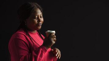 africano americano mulher imerso dentro prazer do bebericando café perdido dentro contemplação olhando para cima. fêmea moda blogueiro sabores dela caloroso bebida com sentido do satisfação. vista lateral retrato. foto