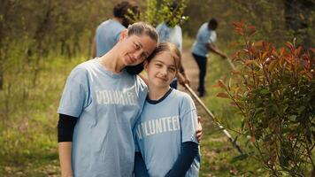 retrato do mãe e filha voluntariado para limpar \ limpo acima uma floresta área, mostrando uma sentido do devoção e responsabilidade para a natural meio Ambiente conservação. ecológico justiça. Câmera uma. foto