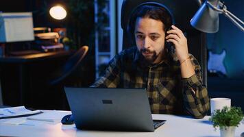 trabalhador autonomo fazendo computador tarefas para equipe projeto dentro pessoal casa escritório enquanto ouvindo música. controlo remoto empregado trabalhando atrasado às noite, digitando em computador portátil teclado, colocando fones de ouvido sobre, Câmera uma foto