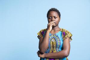 contemplativo jovem mulher parece cauteloso dentro frente do a Câmera, considerando questão antes chegando para uma decisão. africano americano menina dentro estúdio contemplando e é desconfortável. foto