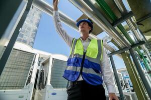 industrial engenheiro ajustando gasoduto válvula com rádio comunicação em construção local. engenheiro em urbano construção local usando rádio para coordenada com equipe em uma ensolarado industrial telhado. foto