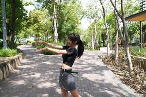 ásia mulher dançando dentro a meio do uma parque foto