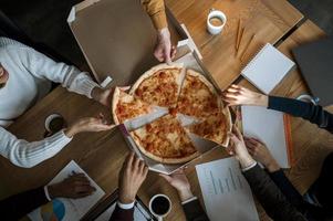 visão superior dos colegas comendo pizza durante o intervalo da reunião do escritório foto