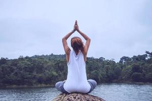 mulheres asiáticas relaxam no feriado. jogar se ioga. nas rochas no meio da água. foto