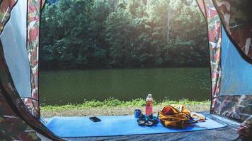 natureza de viagens. viajar relaxar. mochila e calçado telemóvel com um conjunto traveller.sun colocado na frente da tenda de campismo. fundo da natureza do Lago de montanha. foto