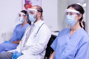 equipe médica de uniforme e máscara protetora olhando para a câmera