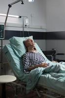 homem idoso sofrendo após acidente grave deitado em uma cama de hospital foto