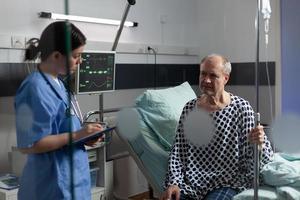 equipe médica com estetoscópio questionando homem idoso doente foto