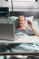 homem idoso doente e alegre acenando para a câmera durante a videoconferência