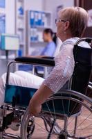 closeup de mulher idosa com deficiência em cadeira de rodas, esperando o médico foto