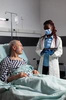 médico com máscara cirúrgica em quarto de hospital discutindo diagnóstico foto
