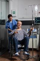 homem idoso hospitalizado sentado em uma cadeira de rodas em um quarto de hospital