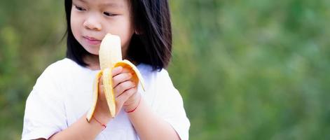 banana nas mãos menina criança. foco seletivo. foto