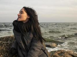 menina sentada em uma pedra perto do mar foto