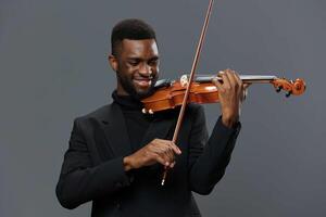 africano americano homem jogando violino em cinzento fundo, exibindo talento e paixão para música foto