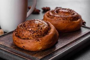 Pãozinho de canela recém-assado com especiarias e recheio de cacau em um fundo preto foto