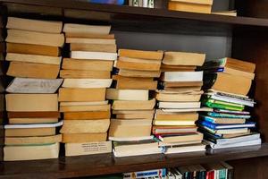 livros velhos amarelados empilhados na prateleira da estante, biblioteca. foto