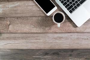 mesa de escritório de madeira com computador e telefone inteligente com xícara de café foto