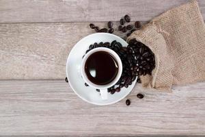 xícara de café e grão de café na mesa de madeira foto