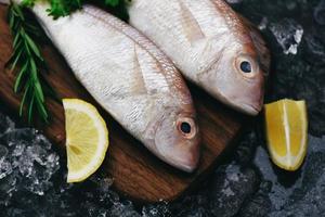peixe cru fresco com ingredientes, limão, alecrim e alface para fazer comida cozida no gelo no mercado de peixes mariscos dourados congelados