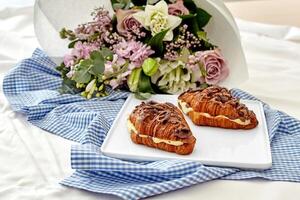 romântico configuração com chocolate garoa croissants e flor ramalhete foto