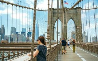 Nova York, EUA - 21 de junho de 2016. turistas tirando fotos na ponte de Brooklyn com o horizonte de manhattan no fundo, na cidade de Nova York