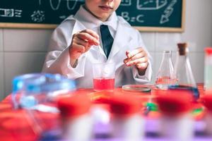 garoto brincando de ser químico com líquidos coloridos foto