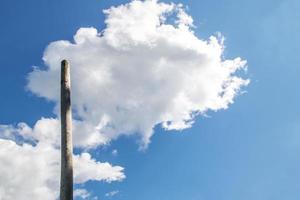 nuvens flutuando em um céu azul perto de um poste de madeira foto