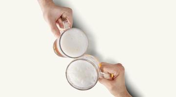 duas mãos brindando uma cerveja gelada refrescante. foto