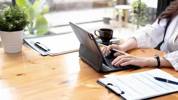 close-up mulher de negócios usando calculadora e laptop para fazer finanças matemáticas na mesa de madeira no escritório e negócios trabalhando fundo, impostos, contabilidade, estatísticas e conceito de pesquisa analítica foto